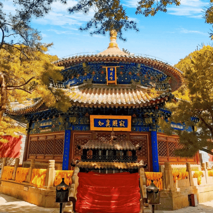 A colorful traditional Chinese pagoda temple with gold and blue details surrounded by autumn trees.
