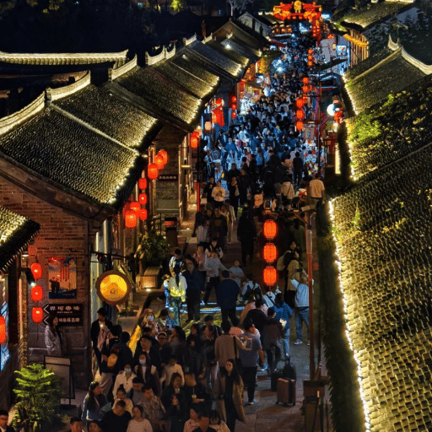 Crowded night market in a historic Chinese town with red lanterns and traditional tiled roofs.