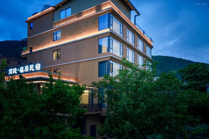 Modern boutique hotel exterior with glowing lights and large glass windows at dusk.