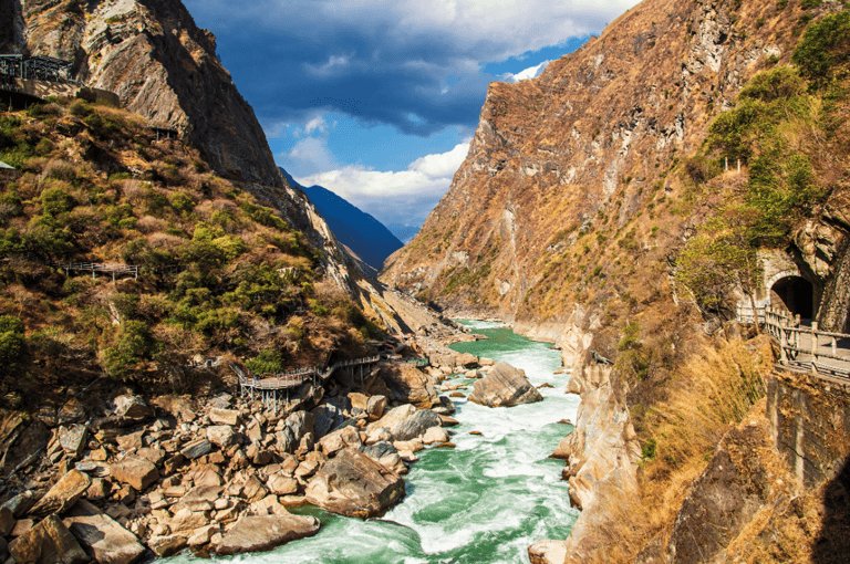A scenic view of Tiger Leaping Gorge with the Jinsha River flowing between steep canyon cliffs in Yunnan, China.