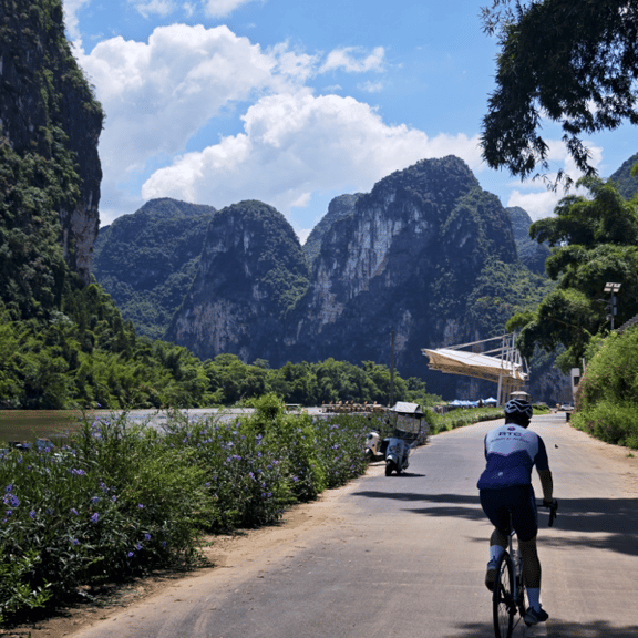 Cyclist riding along the Li River with dramatic karst mountain views in Yangdi Wharf Yangshuo