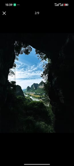 Scenic view of Li River and karst mountains in Guilin, China, seen from inside a dark cave opening.