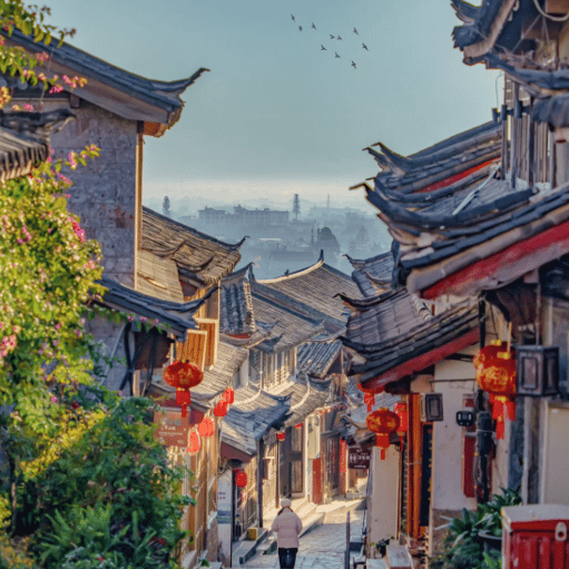 Scenic narrow street in Lijiang Old Town with traditional tiled roofs and red Chinese lanterns.