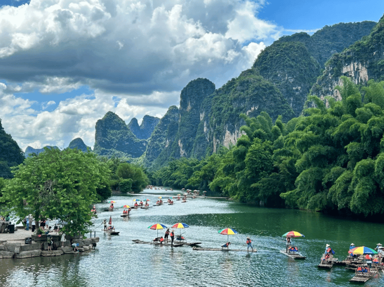 Tourists on bamboo rafts floating down the Yulong River surrounded by karst mountains in Yangshuo, China.