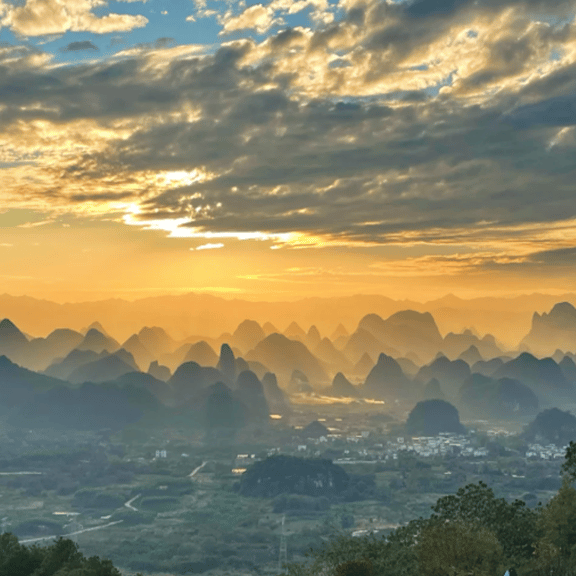 Golden sunset over the karst mountain peaks of Guilin, China, with mist covering the valley floor.