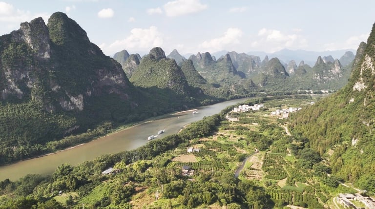 Aerial view of the Li River winding through lush karst mountains and rural farmland in Guilin, China.