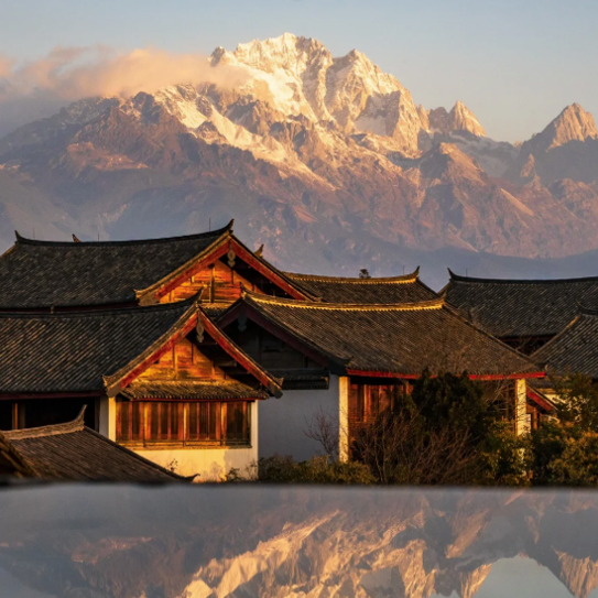 Traditional Chinese architecture in Lijiang Old Town with Jade Dragon Snow Mountain at sunset.