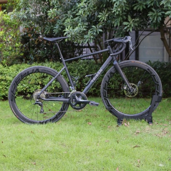 A matte black Triban RC500 road bike with deep section carbon wheels parked on a green lawn.